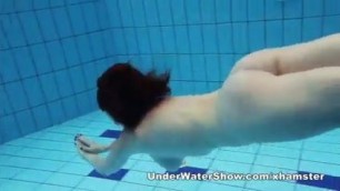 Redheaded cutie swimming nude in the pool